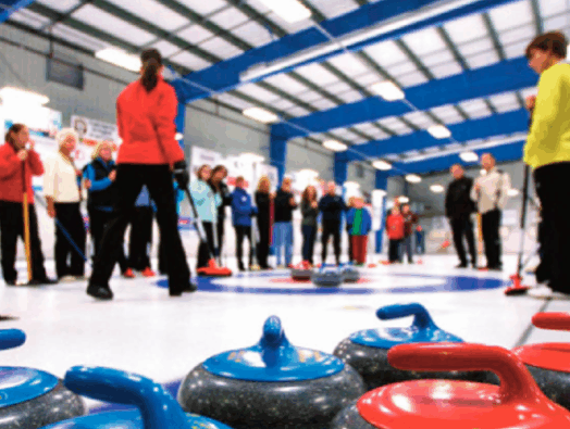 Clinic instructor out on the curling ice with new curlers
