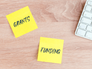 Desk with sticky notes that say "Grants" and "funding"