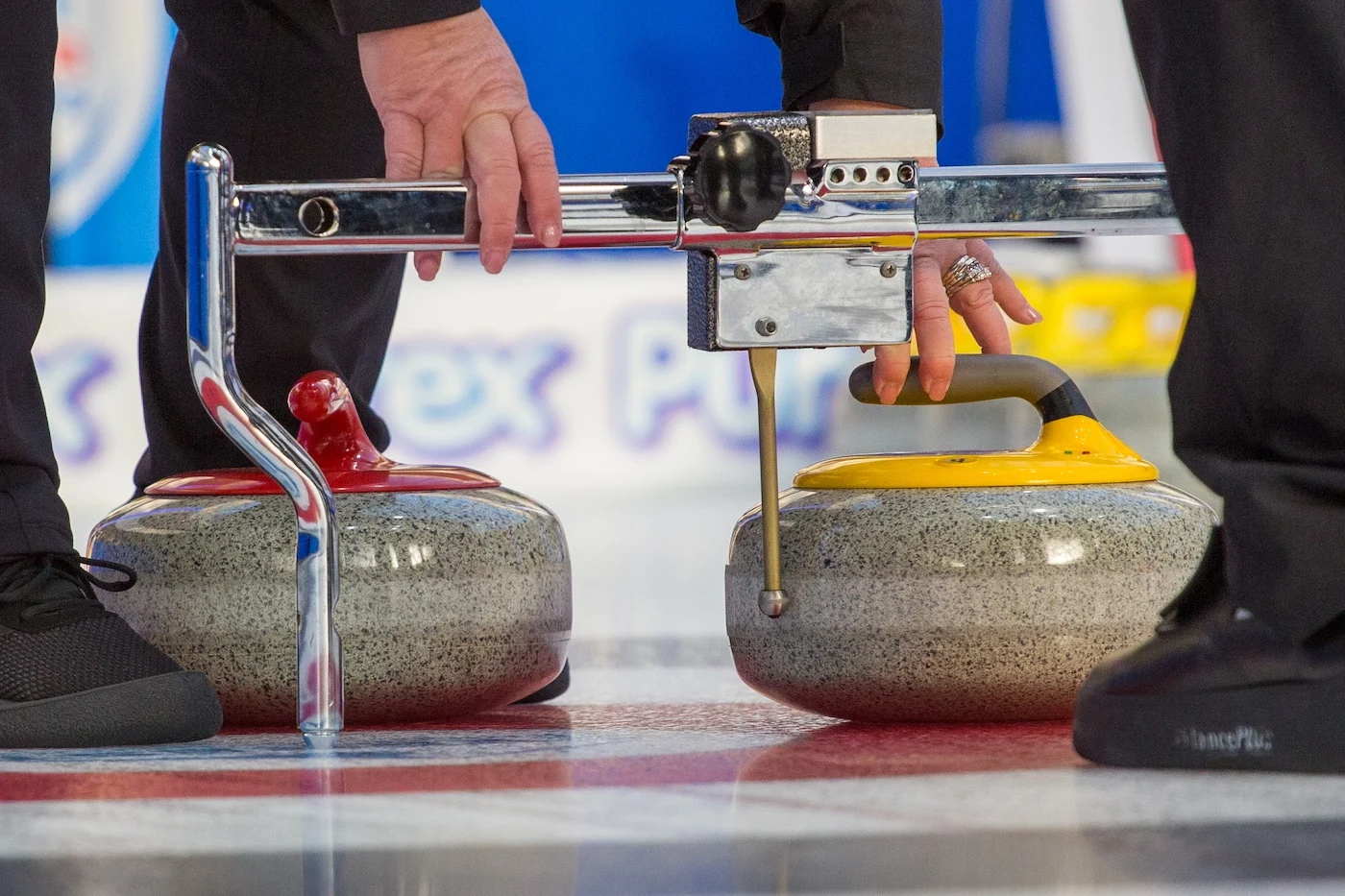 image of curling officials measuring two curling rocks.