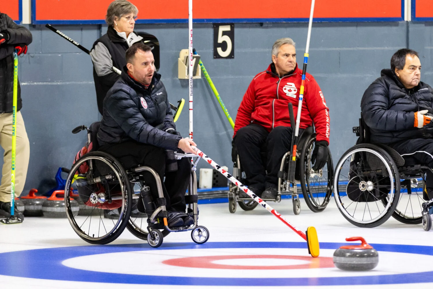 wheelchair curler holding the broom in the house out on the curling ice