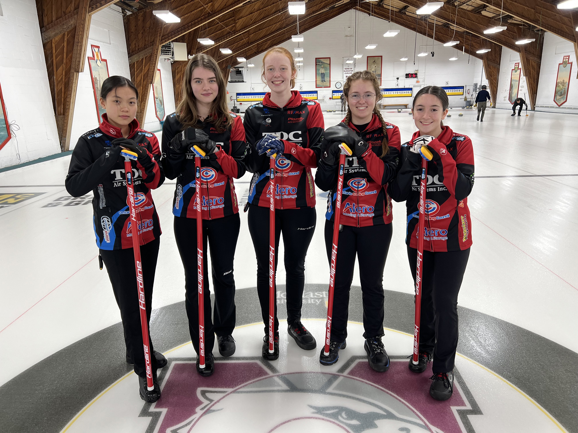 Women's U18 Academy Team posing on the curling ice