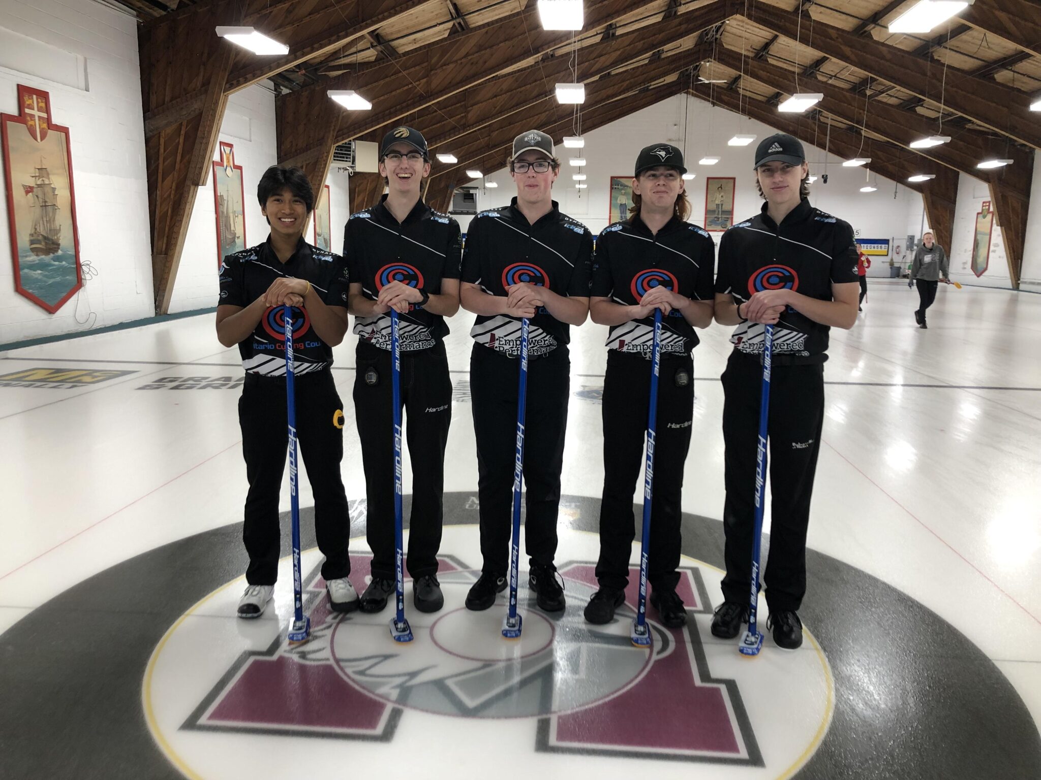 Men's U18 Academy Team posing on curling ice