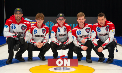 male athletes posing infront of ON sign on curling ice