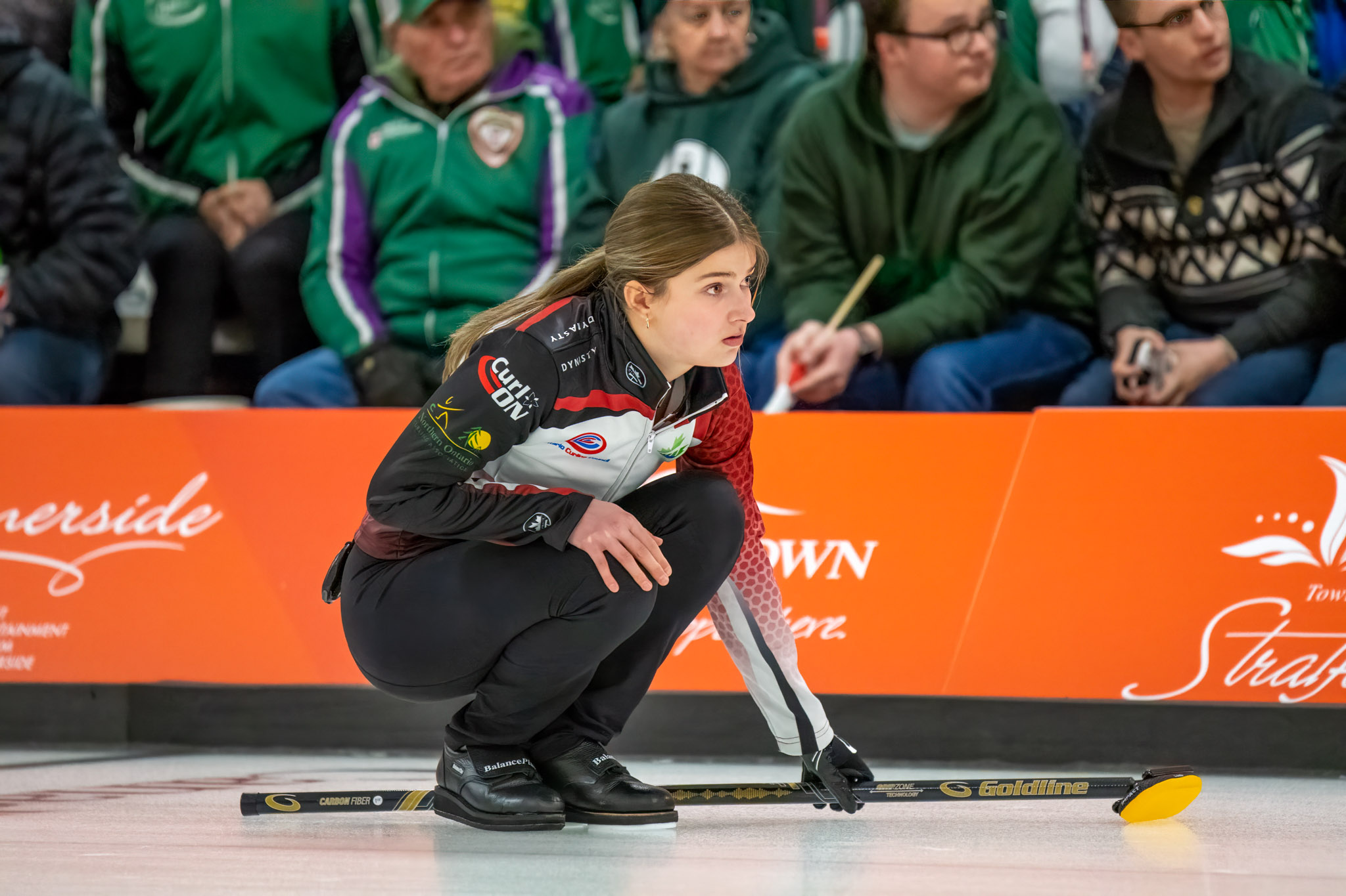 Next Gen female athlete watching her shot go down the ice at a competition