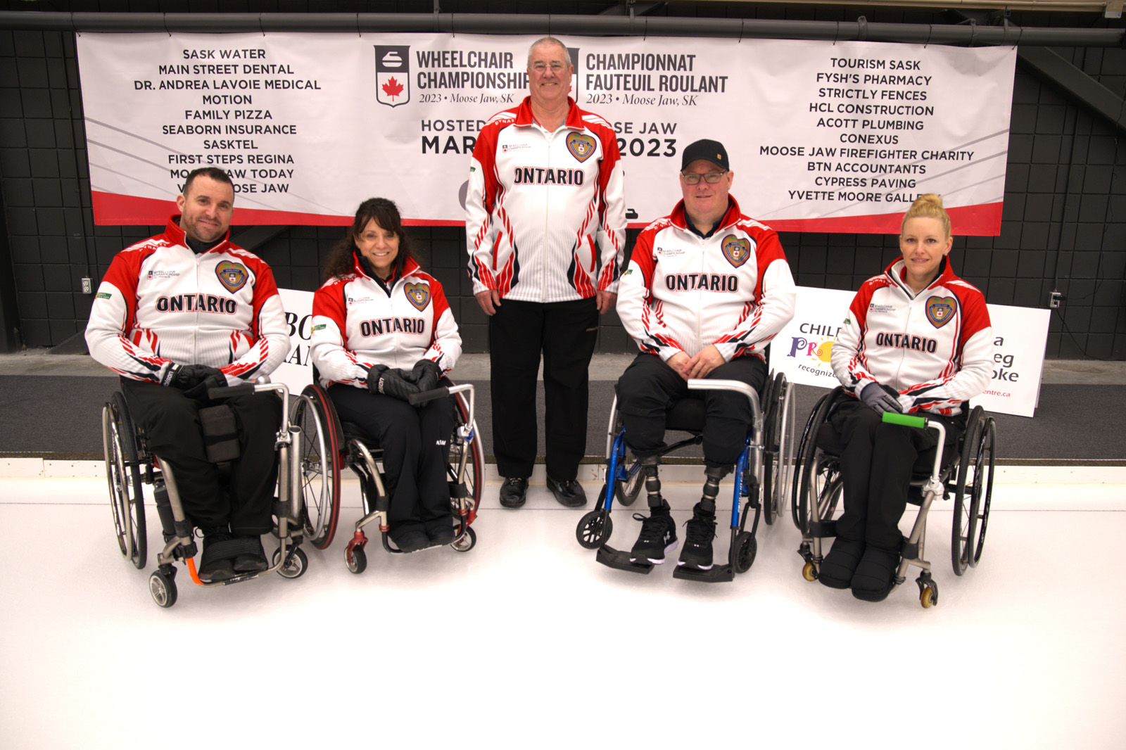 Ontario Wheelchair Curling Team posting on the ice with their coach at Nationals